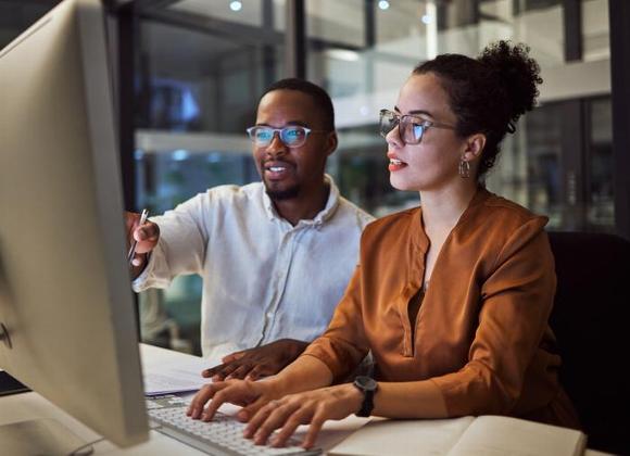 man and woman looking at computer screen in office