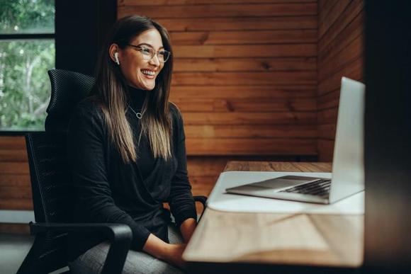 lady smiling and sitting in front of laptop in home office