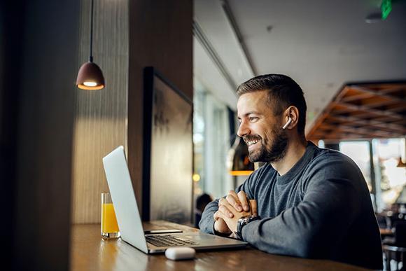 man smiling at laptop in cafe